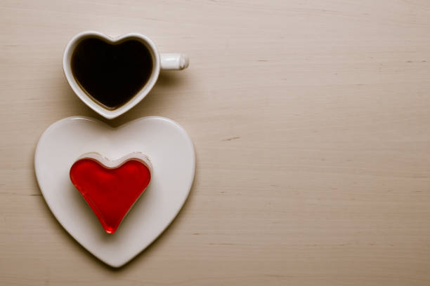 istock Heart shaped coffee cup and cake on wood surface 696778520