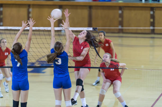 Girls high school volleyball team Volleyball player leaps up to spike while her opponents try to block it secondary school activities stock pictures, royalty-free photos & images