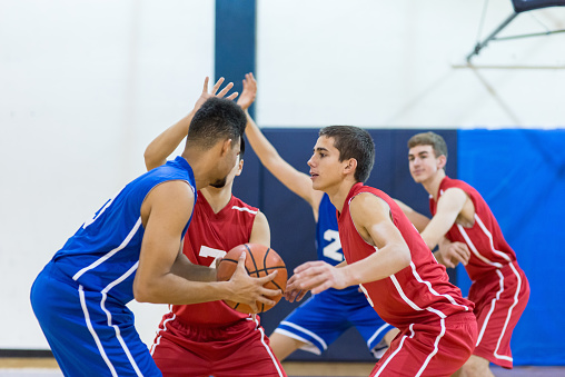 Boys high school basketball team:player prepares to drive toward hoop while defender guards him closely