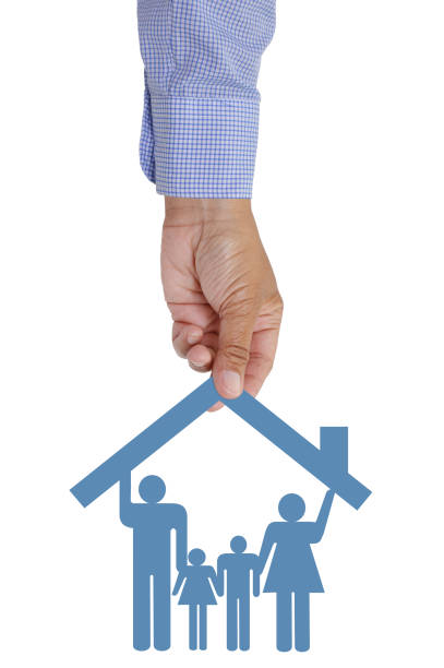 Hand holding paper doll family under blue house roof isolated on white background