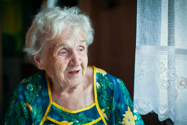 istock Elderly women sadly looking out the window. 696796542