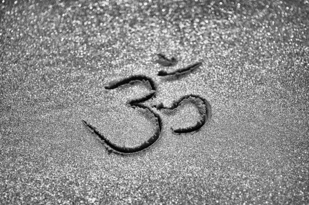 Sacred Sanskrit Om symbol handwritten in textured sand with selective focus bokeh effect