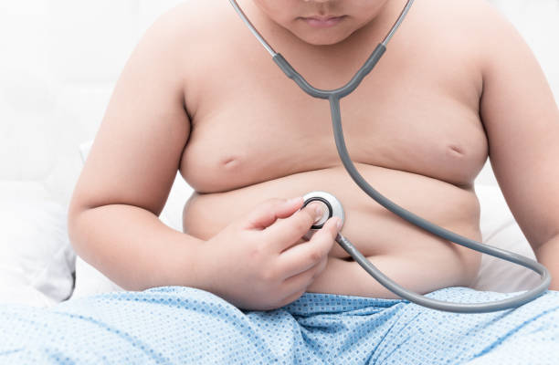 istock Obese fat boy check stomach by stethoscope. 696799662