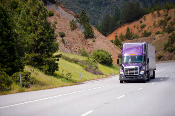 caminhão de lilás semi reboque de alumínio está se movendo ao longo da estrada sinuosa na passagem na califórnia, no contexto das encostas laranja - flatbed truck truck truck driver heavy - fotografias e filmes do acervo
