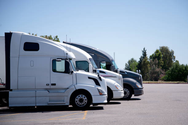 Modern semi trucks stand in row on truck stop parking space Modern big rigs semi trucks stand barely in the parking lot, waiting for the next time on the schedule to load and drive trucks to the next delivery destination car carrier semi stock pictures, royalty-free photos & images