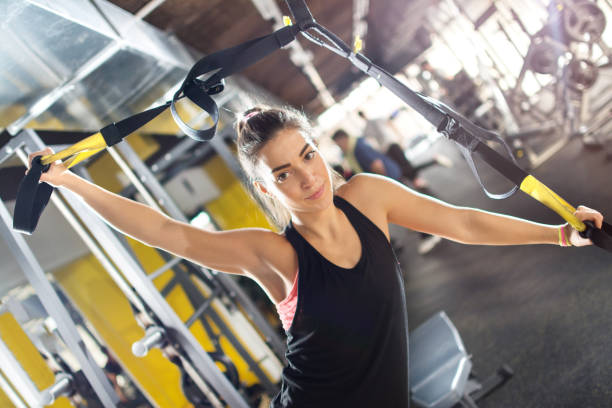 istock Young woman doing exercises with suspension straps at gym. 696844834