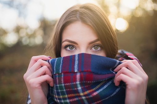 Portrait of a beautiful young woman with face wrapped with a plaid scarf.