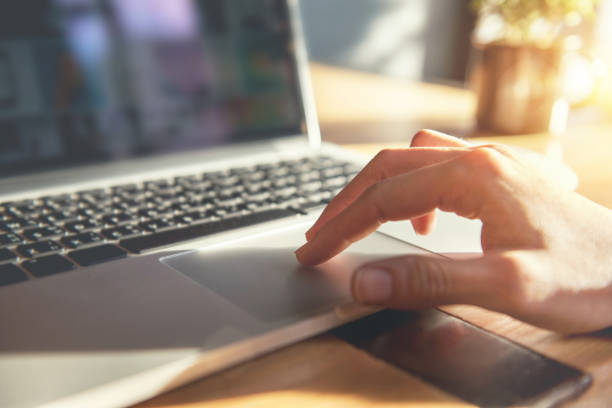 Woman hand using touchpad on laptop at home Woman hand using touchpad on laptop at home touchpad stock pictures, royalty-free photos & images