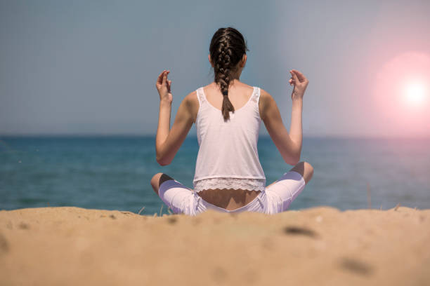 istock Young yoga woman meditating on the beach 696868558