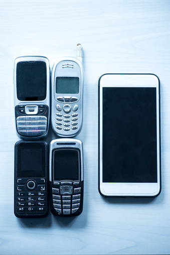 Some old pobile phones compared to a modern smartphone.
