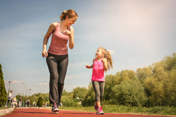 Caucasian mother and daughter jogging outdoors. Mother and daughter enjoying together. stock photo