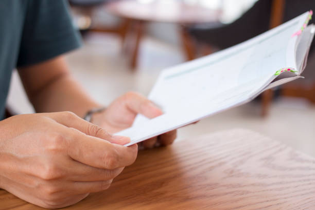 istock Man holding orange notebook on wooden table. 696872322
