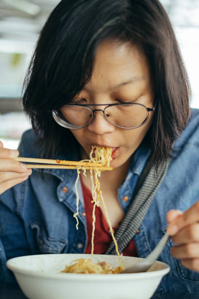 istock Women eating egg noodle with crispy pork from chopsticks and metal spoon 696877610