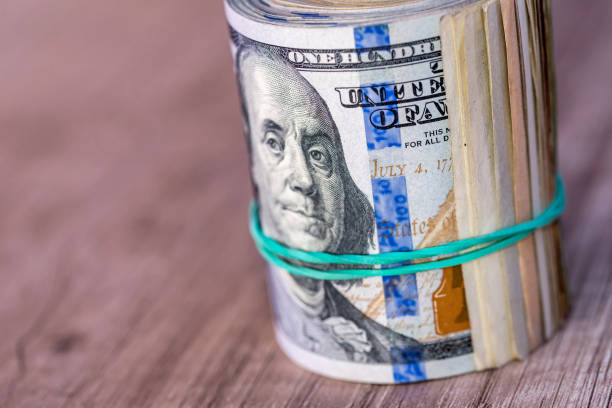istock dollar roll with clipping path on wooden background close up. 696881064