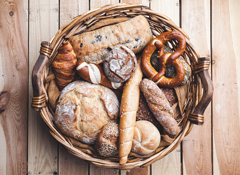 A basket full of delicious freshly baked bread on wooden background
