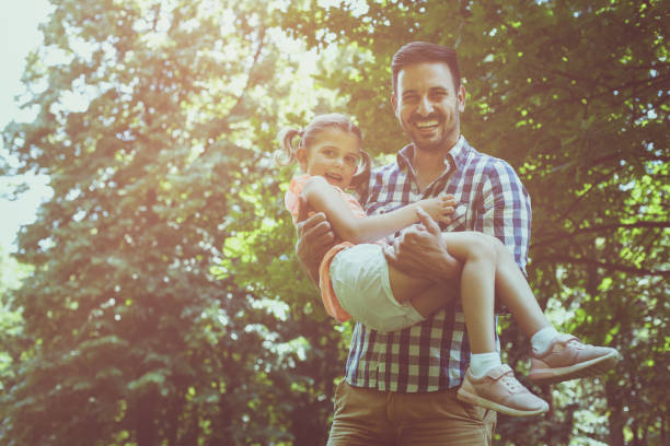 istock Father holding his daughter in his arms and looking at camera. 696885268