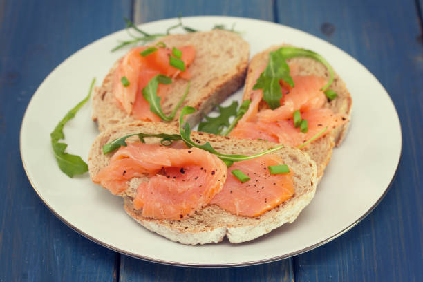 istock bread with smoked salmon on white plate on blue wooden background 696885336
