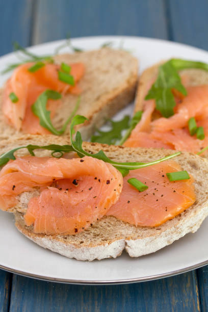 istock bread with smoked salmon on white plate on blue wooden background 696885344