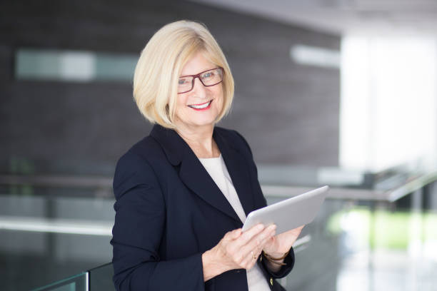 istock Happy Senior Business Lady Using Tablet in Lobby 696885744