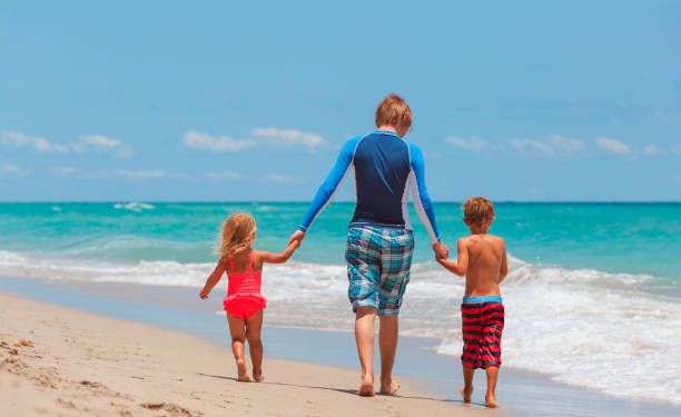 istock father and two kids walking on beach 696886604