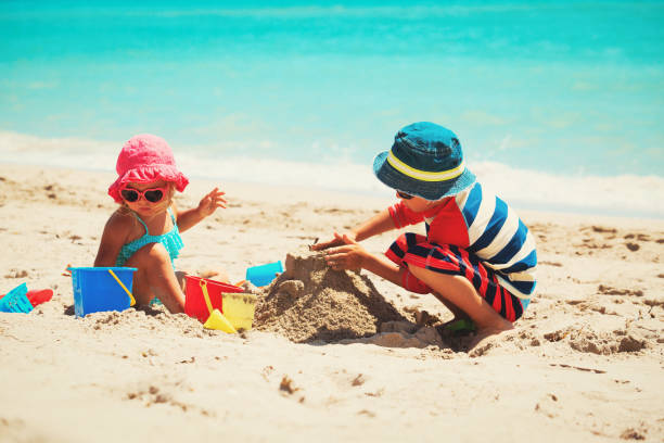 istock little boy and girl play with sand on beach 696889202