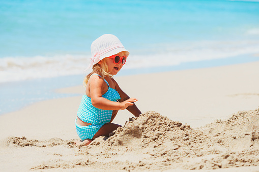 cute little girl play with sand on tropical beach