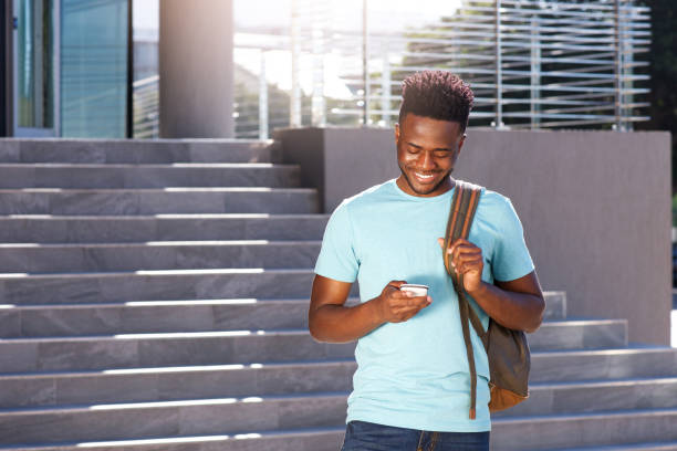 smiling african american student looking at cellphone Portrait of smiling african american student looking at cellphone men hairstyle afro cool stock pictures, royalty-free photos & images