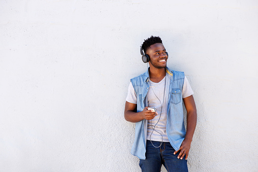 Portrait of cool african guy with mobile phone and headphones listening to music