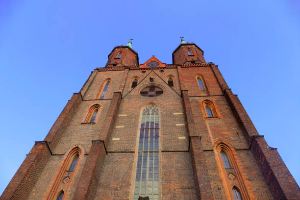 Old church on a hill with a tall tower. Built of red brick against the blue sky is an old building reminiscent of the ancient heritage of Christian Europe.