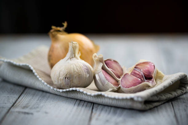 aglio biologico e cipolla su sfondo legnoso - aglio alliacee foto e immagini stock