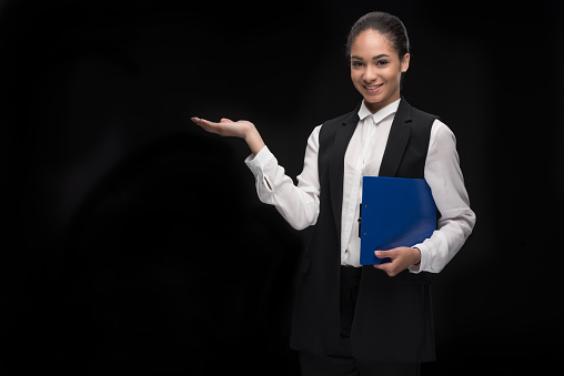 Portrait of young businesswoman standing with clipboard and presenting copy space on palm