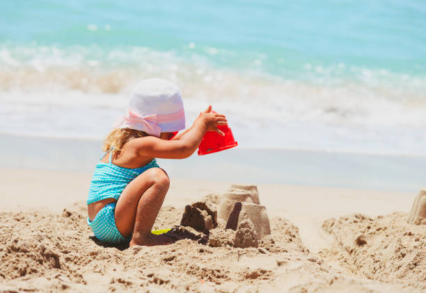 niedlich kleine mädchen spielen mit sand am strand - lifestyles child beach digging stock-fotos und bilder