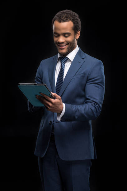 istock Portrait of successful businessman using digital tablet isolated on black 696900690