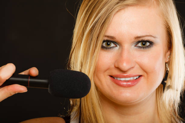 istock Blonde woman singing to microphone 696909748