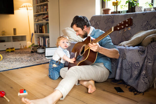 istock Father and son at home playing guitar together. 696912182