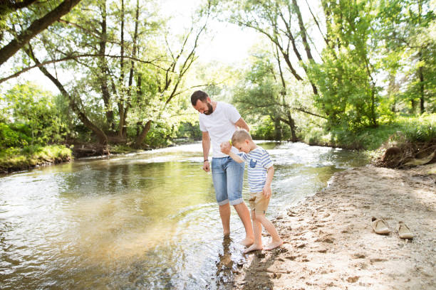 istock Young father with little boy at the river, sunny spring day. 696916130