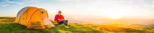 istock Young woman wild camping on mountain summit summer sunset panorama 696916538