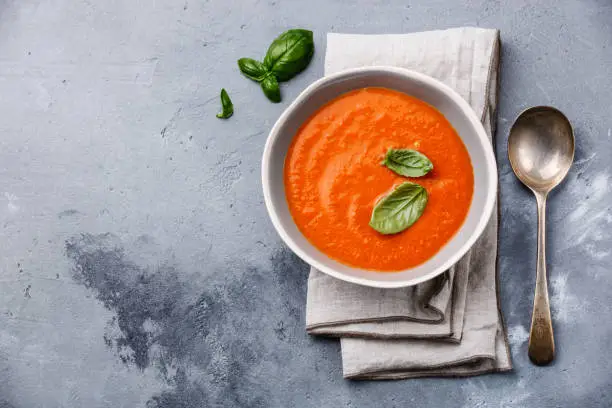 Gazpacho soup with green basil on grey concrete background