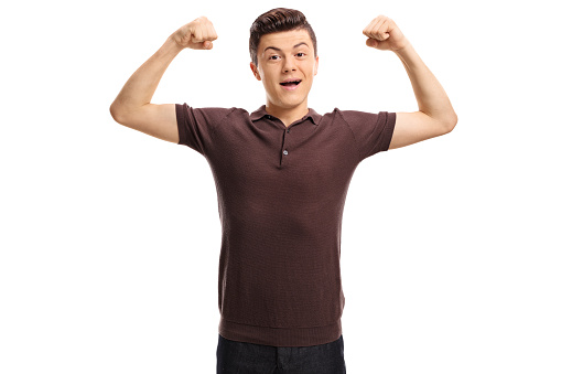 Teenager flexing his muscles and looking at the camera isolated on white background