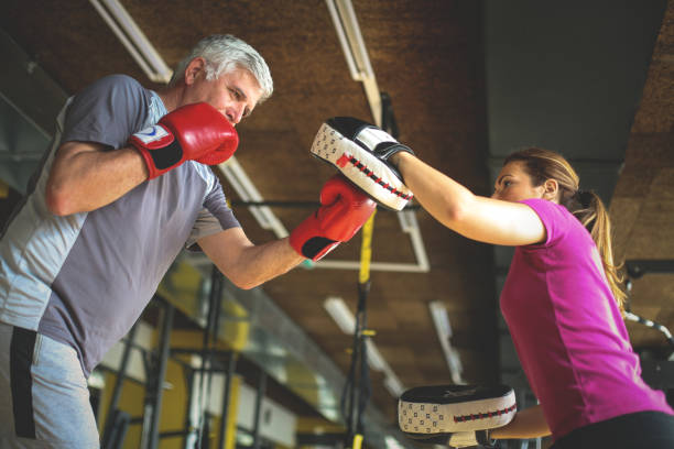 istock Older man boxing in gym. Senior man with personal trainer. 696928526