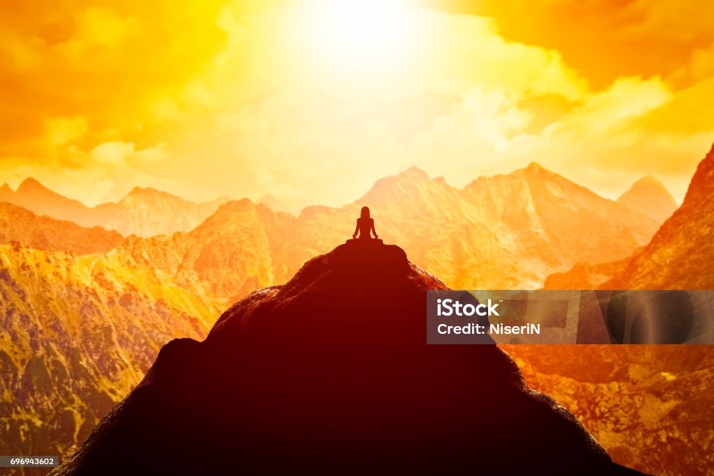 Woman meditating in sitting yoga position on the top of a mountains above clouds at sunset. Woman meditating in sitting yoga position on the top of a mountains above clouds at sunset. Zen, meditation, peace Wellbeing Stock Photo