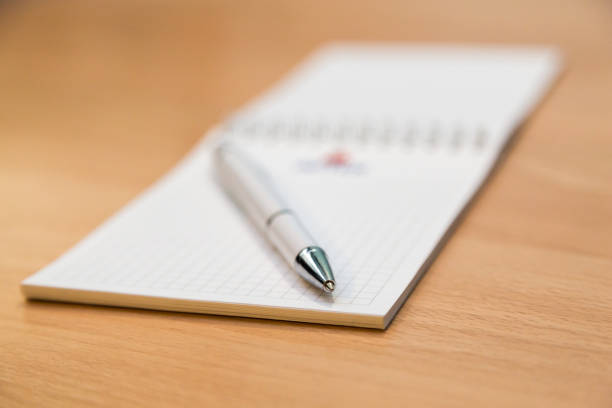 istock A notebook and ballpoint pen lying on a wooden table 696962622