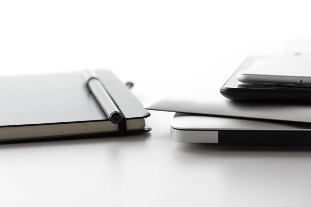 istock laptop computer, tablets and mobile phone besides notebook journal and black pen on white desktop surface 696967052