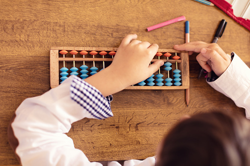 Little boy doing mathematics with abacus. View from above