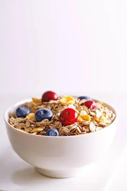 Cereals with berries in a bowl. Healthy breakfast with fresh fruits isolated on white background