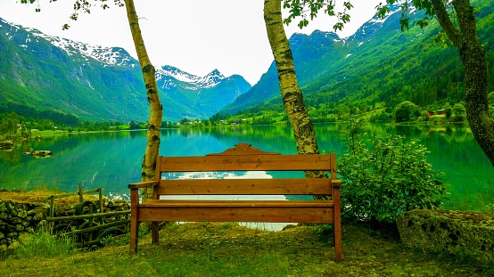 Olden, Norway - June 04, 2014:View of serene mountains landscape, bench with on fjord shore, Olden village in Sogn og Fjordane county, Norway Europe.