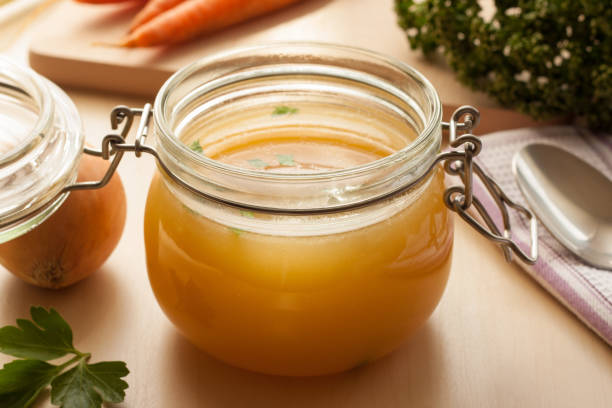 Bone broth made from chicken Bone broth made from chicken in a glass jar, with carrots, onions, and celery root in the background gravy photos stock pictures, royalty-free photos & images