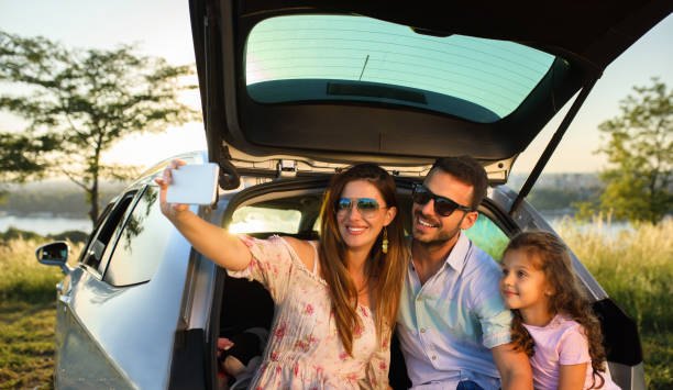 Happy married couple with two daughters are happy after buying a new car in a modern car dealership. The concept of expensive purchase and happy family life.