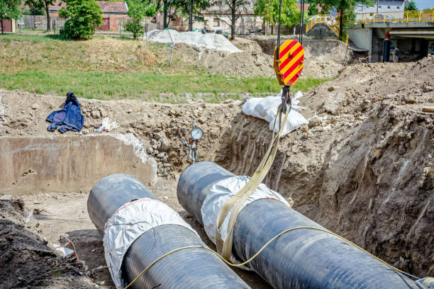 istock Mobile crane is carry long pipe over trench 697019824