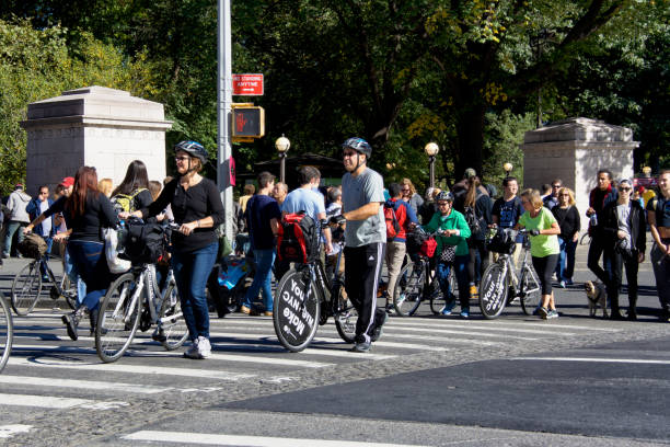 Urban Life, New York City. Bicyclists and Pedestrians crossing Central Park West, Manhattan. New York City, USA - October 15, 2016: Urban life scene. Bicyclists and a crowd of pedestrians are seen walking across Central Park West at Columbus Circle, Upper West Side of Manhattan. city street street corner tree stock pictures, royalty-free photos & images
